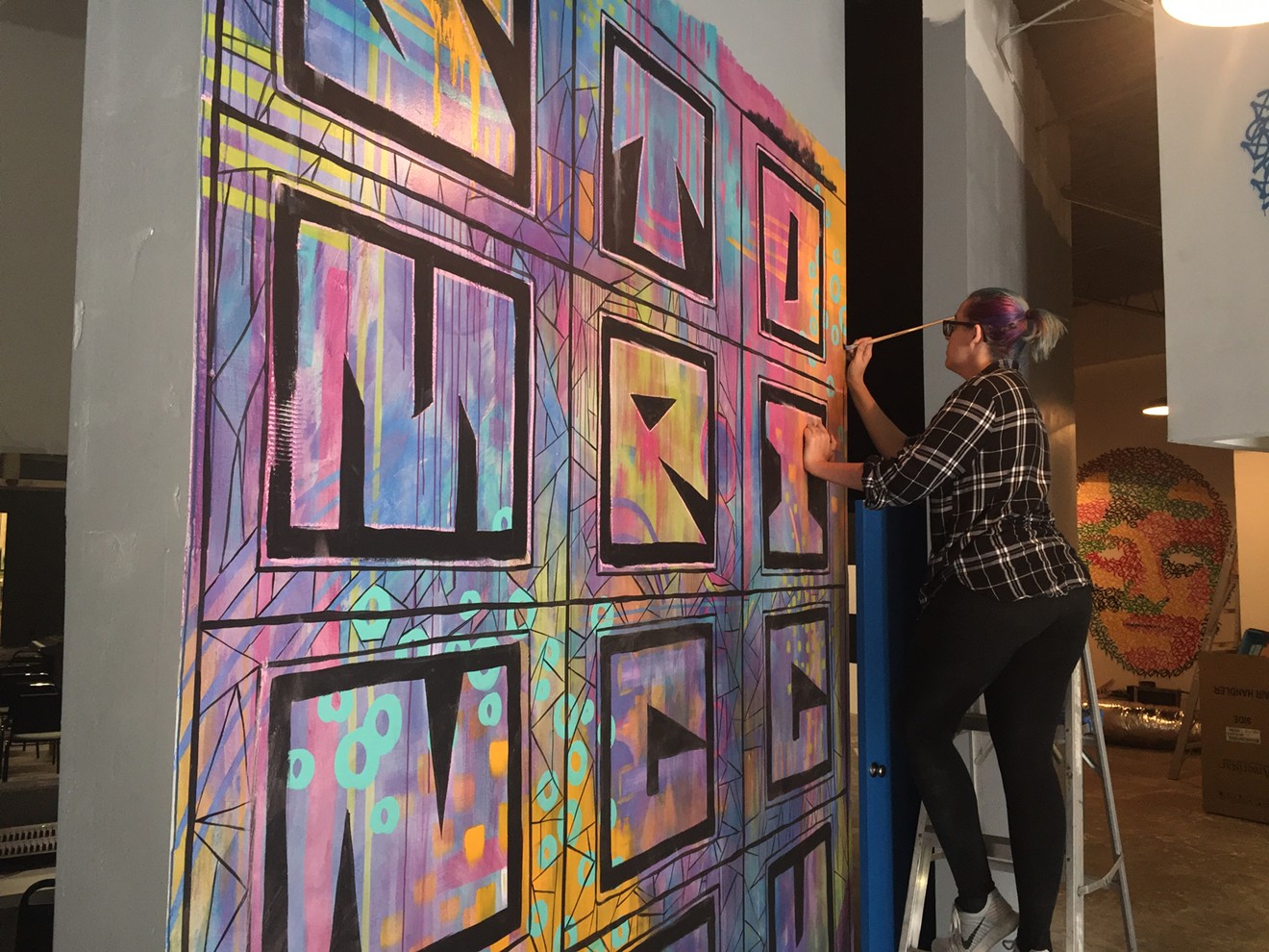 Artist Sarah Luthans paints a mural in the lobby of Stomping Ground Comedy Theater's new location on Manufacturing Street.