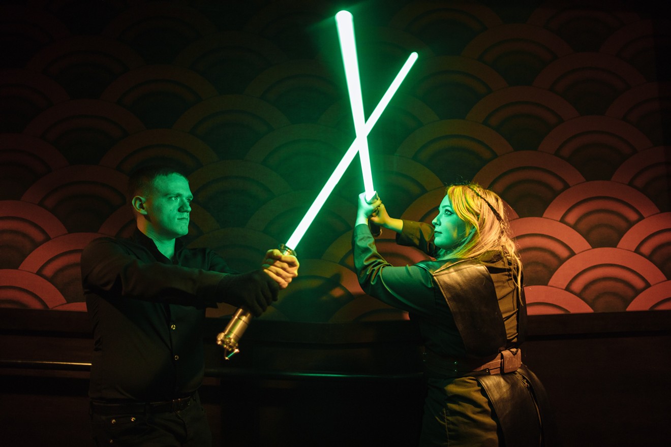A pair of Star Wars fans play with their lightsabers in the lobby of the Alamo Drafthouse Richardson before the premiere of Star Wars Episode VII: The Force Awakens.