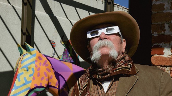 A cowboy stares at the sky wearing eclipse glasses.