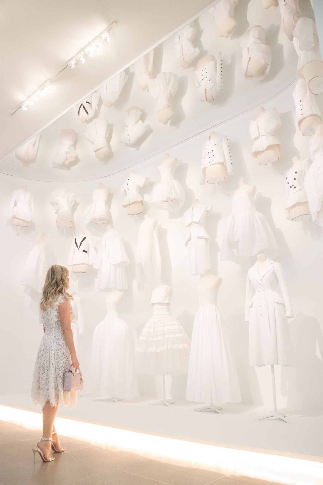 A row of white garments in the dazzling Dior retrospective at the DMA