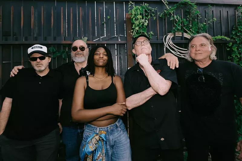 Image: A band standing in front of a fence