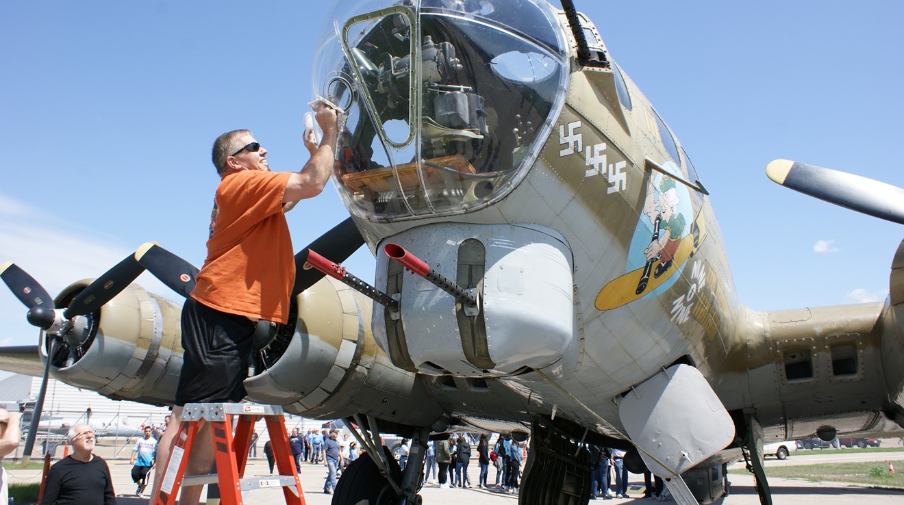Pilot Rick "Thug" Kelly of San Antonio cleans the cockpit glass on a B-17 Flying Fortress plane, a WWII-era aircraft.
