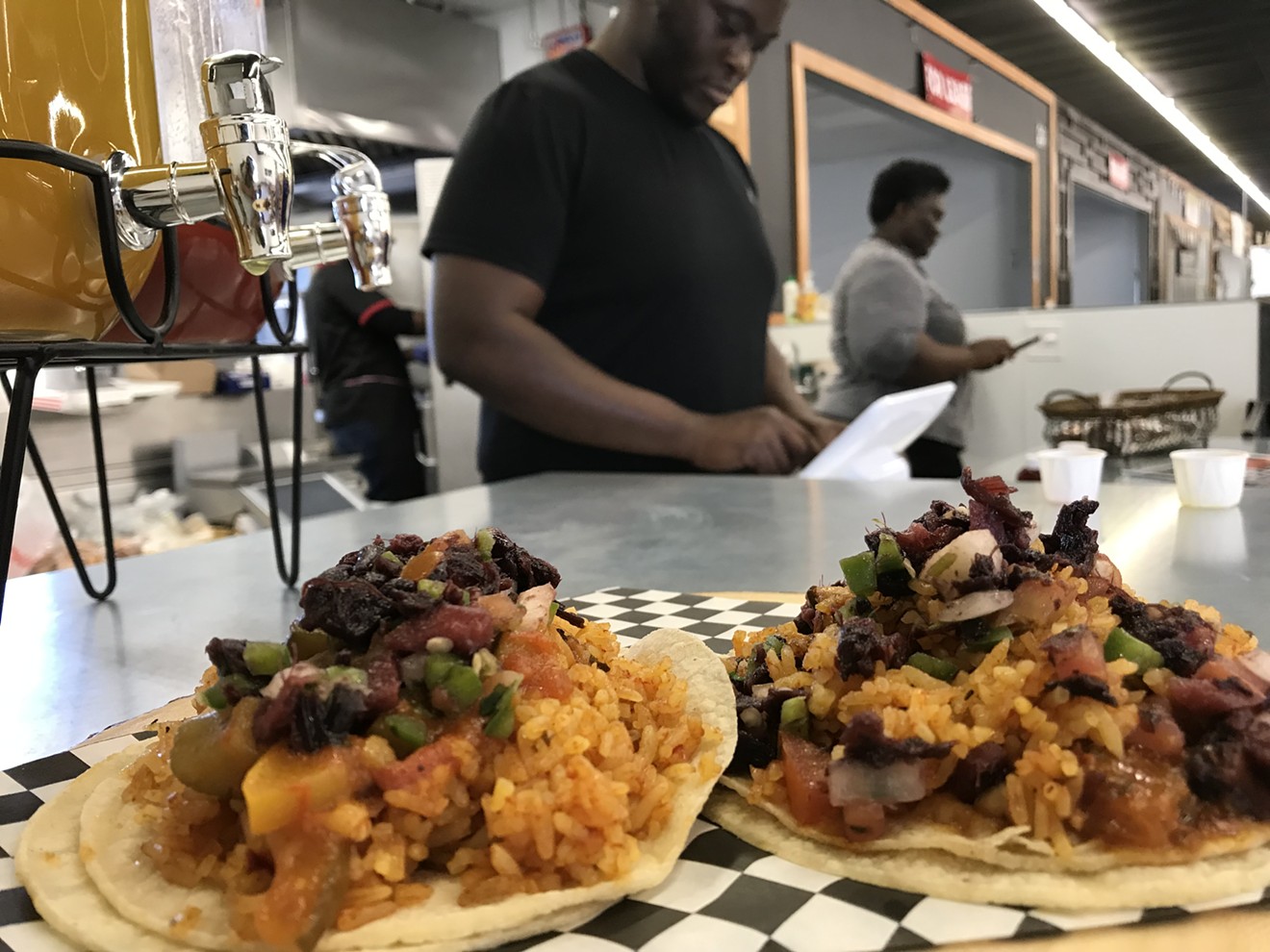 Jollof tacos in the foreground and, in the background, Felix Odu and his mother, Edith, who owns Edylicious in Grow DeSoto Market Place.