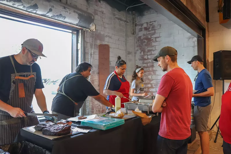 Image: Brandon Mohon (left) slices brisket while the rest of the line prepares food for guests. Eva (far right) had her first job in the Mohon pop-up Sept. 15, working the point-of-sale system, while her mother, Lisa (in the red apron), a trained professional chef, helps prepare items.