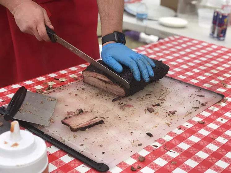 Brandon Mohon of Mohon Barbecue slicing into a smoked brisket at last year's Blues, Bandits & BBQ fest. - BETH RANKIN