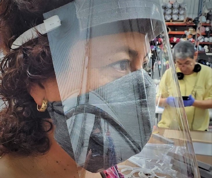 Production floor manager Rocio Gonzalez models a face shield produced by Reflections of Dallas. - REFLECTIONS OF DALLAS