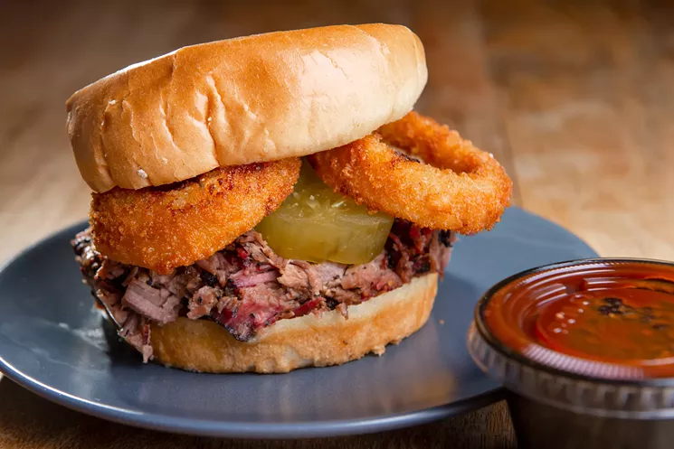 The GF sandwich: Chopped brisket, onion rings, sweet and spicy house-made pickles on a brioche bun, served with barbecue sauce - ALISON MCLEAN