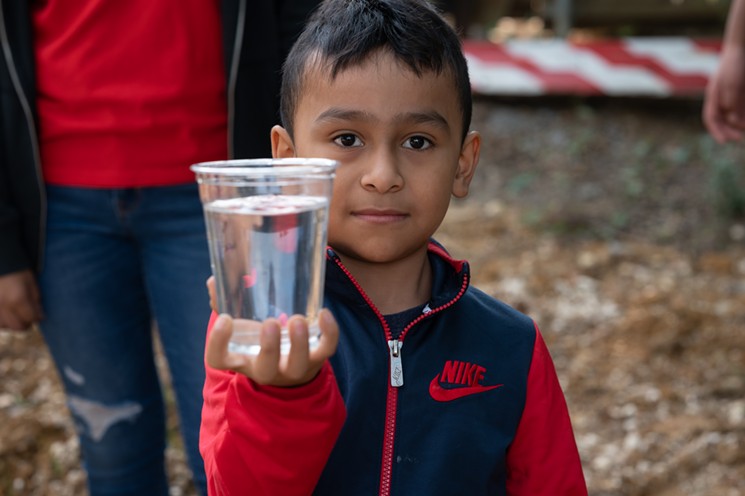 A young resident shows off a clean glass of water. - MIKE BROOKS