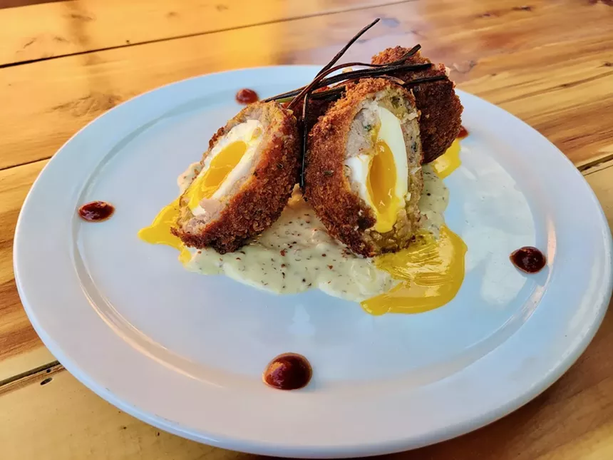 A superbly cooked runny Scotch egg with dollops of Sriracha. - EMAYNE