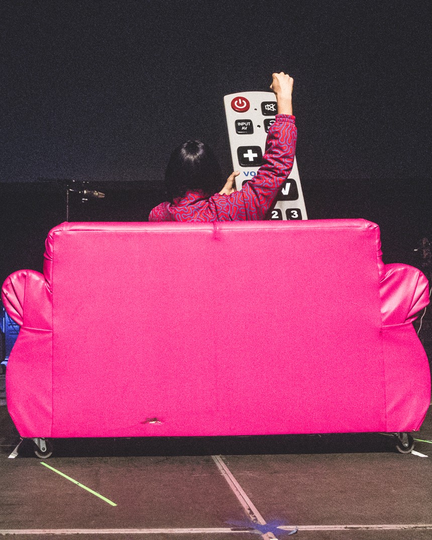 Oliver Tree sits on a pink couch with an giant prop television remote at his show in Dallas.