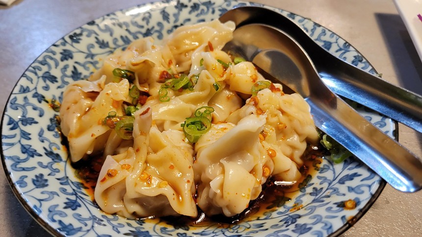 Steamed wontons come in a shallow bowl of black chili vinaigrette.