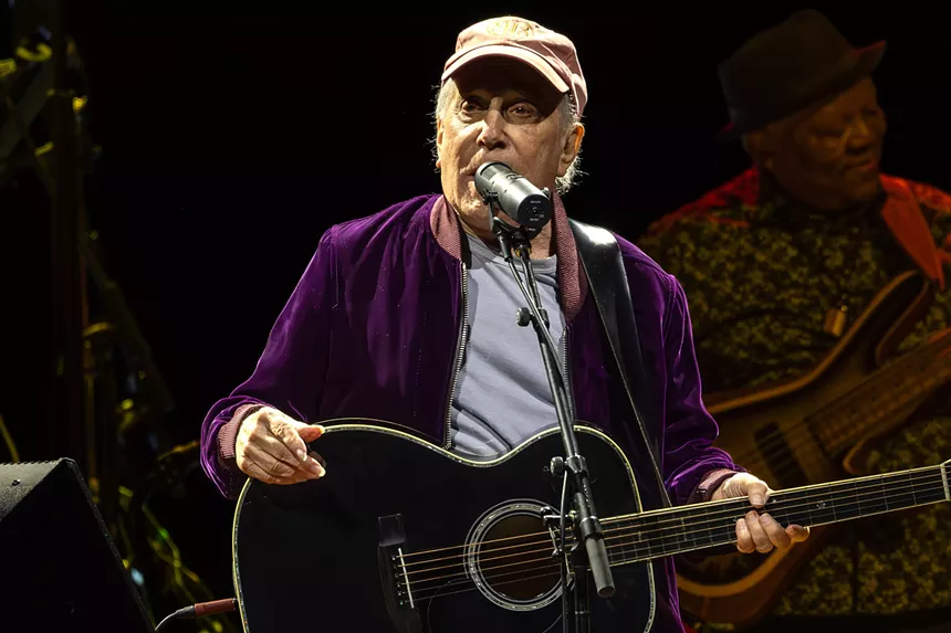 Man performing on stage with a guitar