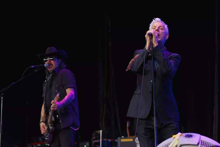 Two men playing guitar and singing on stage.