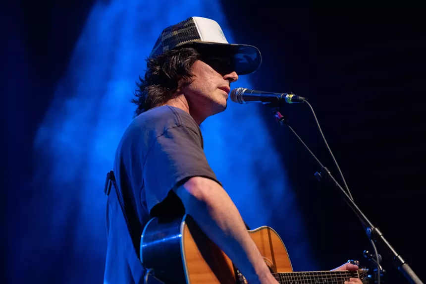 Man performing on stage with a guitar
