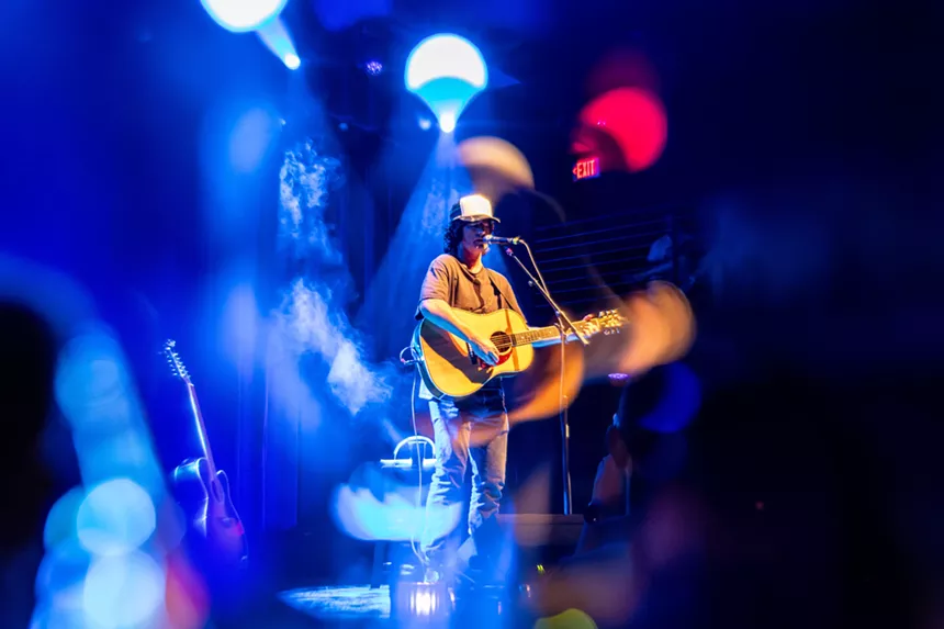 Man performing on stage with a guitar