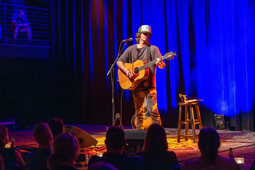 Man performing on stage with a guitar