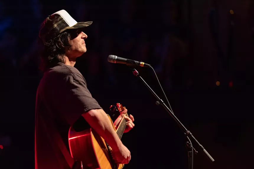 Man performing on stage with a guitar