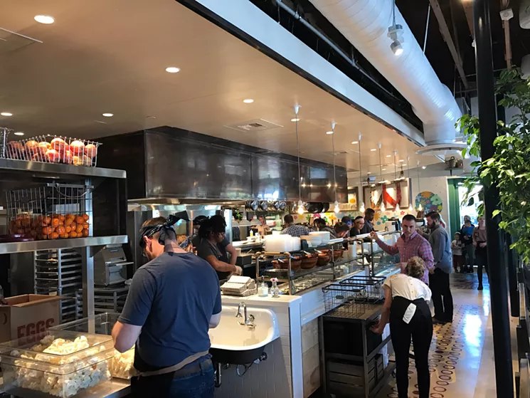 The open kitchen at Flower Child, where fresh fruits and vegtables are piled high in wire baskets. - BETH RANKIN