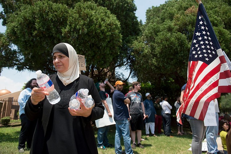 Nora Shuaid hands out water to counterprotestors at the anti-Sharia march. - BRIAN MASCHINO