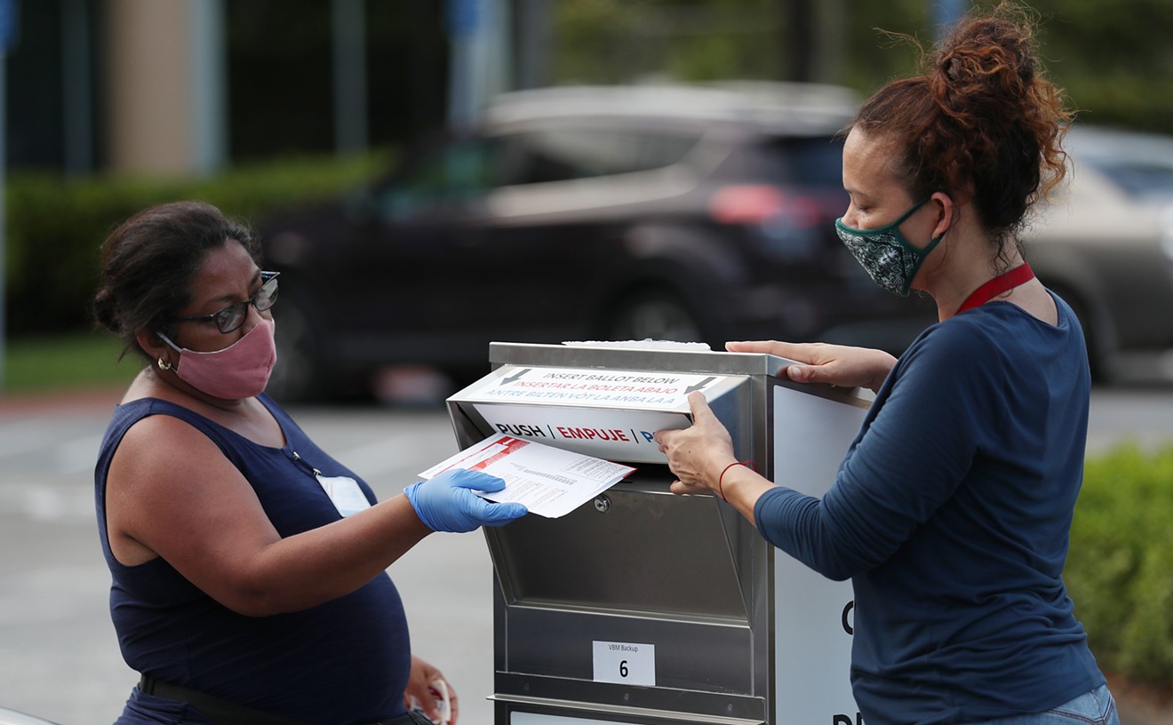 Poll workers deposit people's mail-in ballots into an official ballot drop box on primary Election Day Aug. 18, 2020, in Doral, Florida.