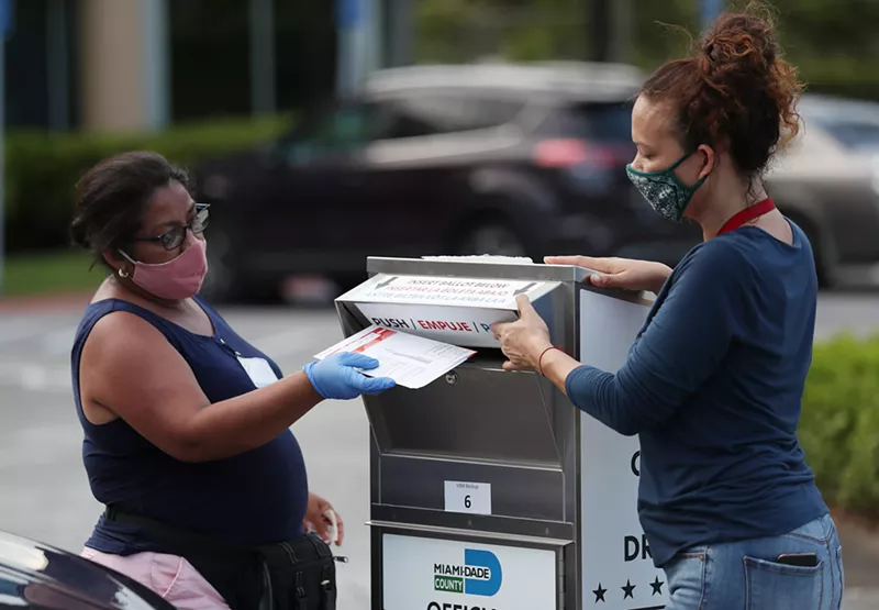 Poll workers deposit people's mail-in ballots into an official ballot drop box on primary Election Day Aug. 18, 2020, in Doral, Florida.