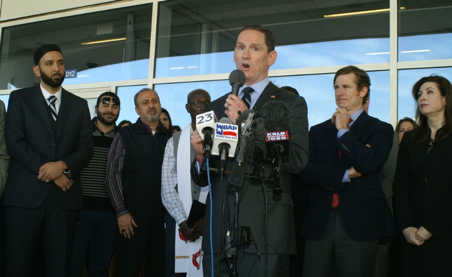 Dallas County Judge Clay Jenkins speaks Wednesday at DFW international Airport outside Terminal D. Ahmed and Tarek Al Olabi are at left, behind the imam and the pastor, while DFW Detained president Chris Hamilton and former Dallas City Council member Angela Hunt are at right.