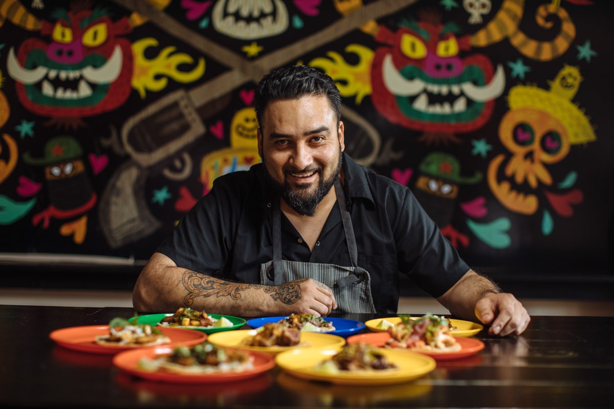 Owner Regino Rojas sits before a spread of tacos in Revolver Taco Lounge.