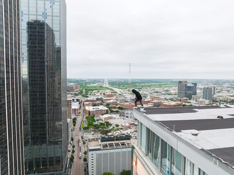 Image: Photographer High Vis looks out over the edge of the Mosaic building in downtown Dallas.