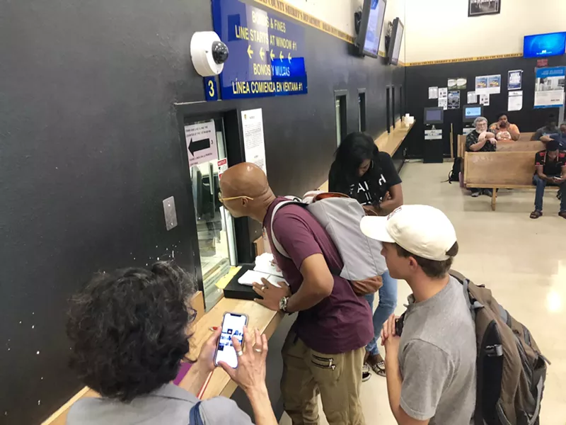 Image: Greg Guggenmos (right) watches Christian Watkins (center) speaking with jail staff before handing over $21,000 in cash that would bail out 16 people.