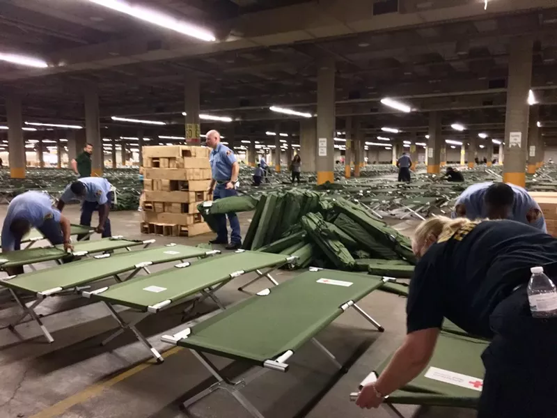 Image: Dallas Fire and Rescue personnel set up cots in the convention center's parking garage.