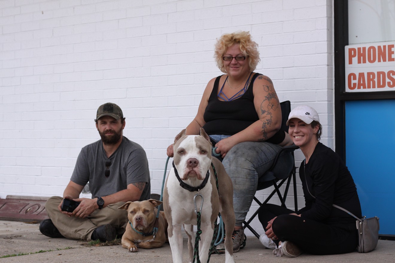 Justin Thomas, Danielle Hollowell and Caitlin Sowell sit outside Moni Food Mart with Hollowell's dogs.