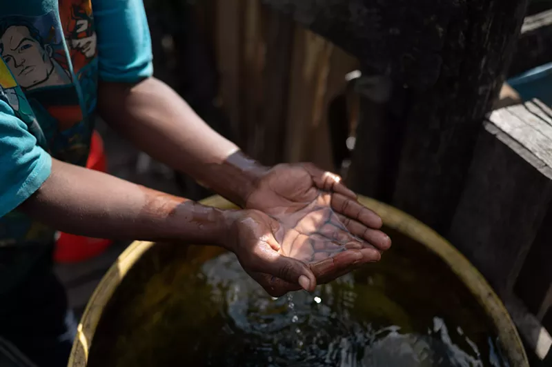 Image: Mahogany Nunnally gathers water in barrels near her home in Sandbranch.
