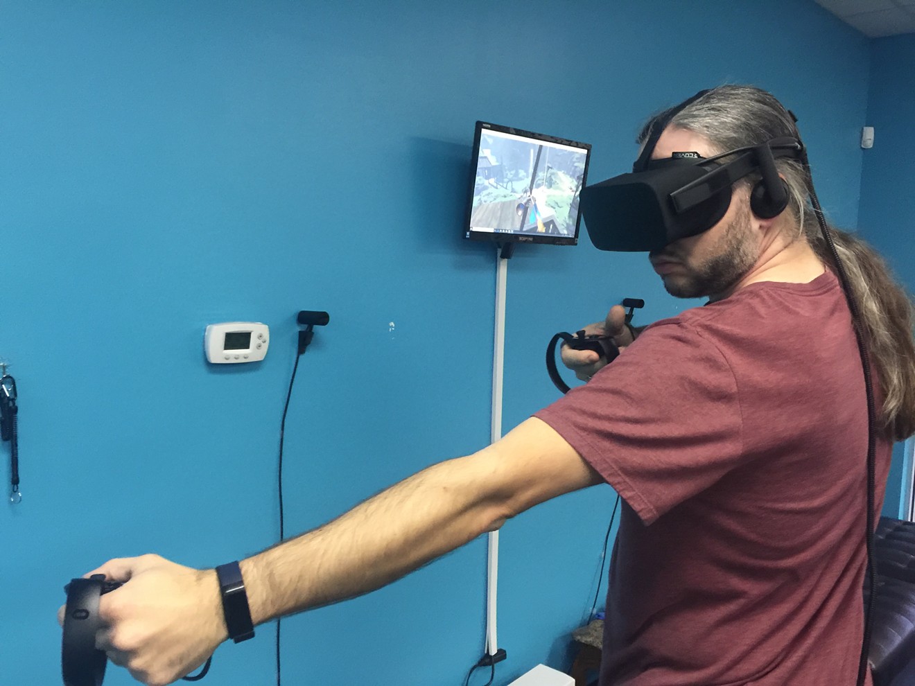 Jerry Nerviano pulls back the string on a virtual bow in the VR game Elven Assassin on an Oculus Rift at ImaginationsVR, a virtual reality arcade based in Allen.